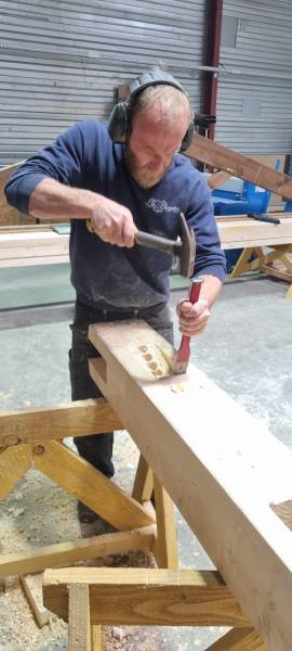 David en pleine réalisation d'un assemblage traditionnelle de charpente. les 2 charpentiers. 