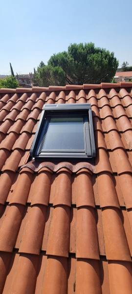 Pose d'une fenêtre de toit de chez vélux  avec le volet roulant électrique sur une couverture en tuile DC12 a Toulouse par les 2 charpentiers.