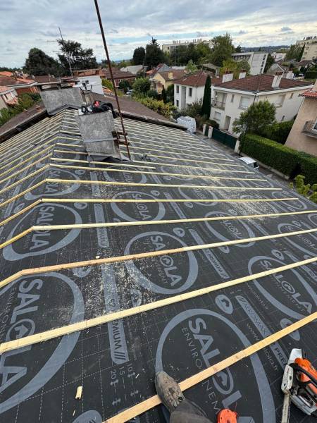 Pose d'un ecran pare-pluie avant la pose de la couverture en tuile par les 2 charpentiers a Albi. 
