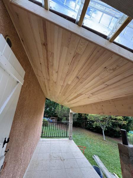 Vue de la terrasse couverte avec finition en lambris bois et tuile de verre pour apport de lumière par les 2 charpentiers a Azas proche d'Albi.  