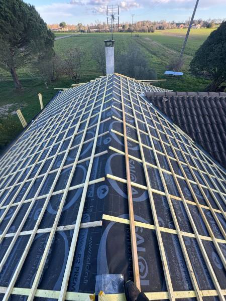 Mise en place des liteaux tuile pour support de nouvelle couverture en tuile romane marron, par les 2 charpentiers, a Roquesérière proche d'Albi. 